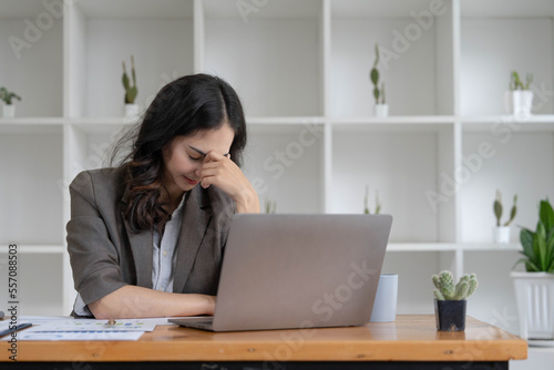 Portrait of serious young businesswoman accountant in formal wear sitting at her work place and use laptop, summarizing taxes, planning future investments, accounting at office.