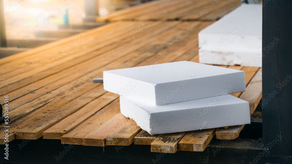 A thick white styrofoam lies at a construction site close-up. Insulation of the house during construction with expanded polystyrene foam A thick white styrofoam lies at a construction site close-up. Insulation of the house during construction with expanded polystyrene foam