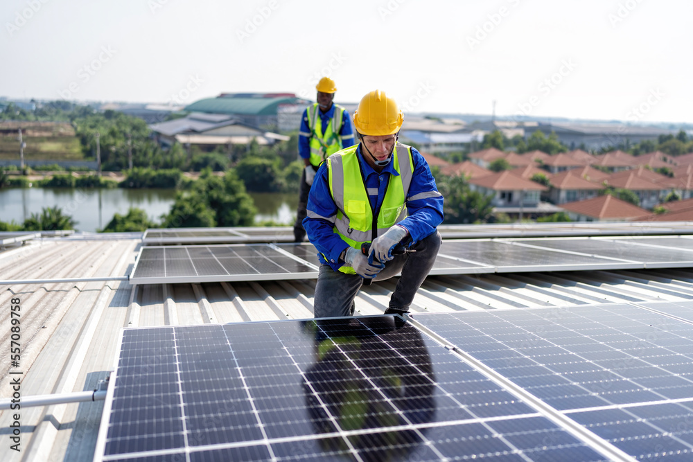 Engineer on rooftop kneeling next to solar panels photo voltaic with tool in hand for installation Engineer on rooftop kneeling next to solar panels photo voltaic with tool in hand for installation