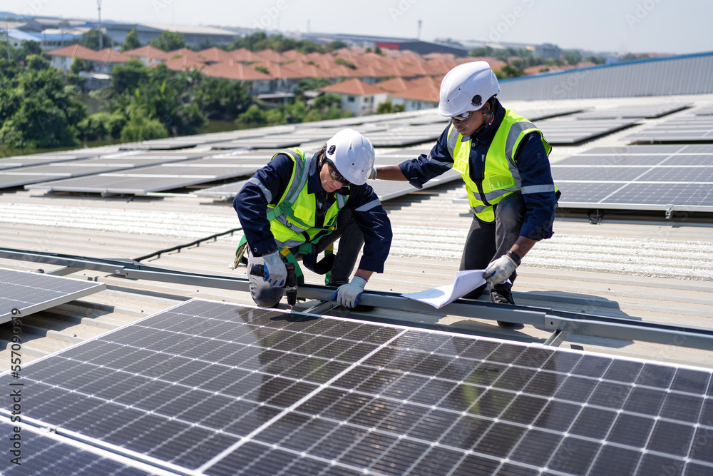 Engineer on rooftop kneeling next to solar panels photo voltaic check drawing for good installation Engineer on rooftop kneeling next to solar panels photo voltaic check drawing for good installation