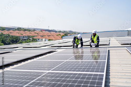 Engineer on rooftop kneeling next to solar panels photo voltaic with tool in hand for installation