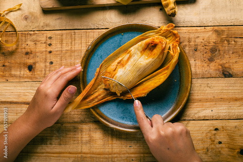 Hands of a person cutting a tamale with a fork. Tamale, typical Mexican food. photo