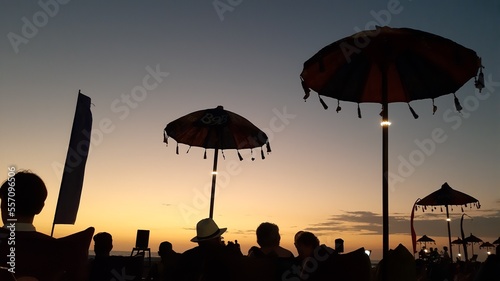 Silhouette People enjoying the sunset view on double six beach in Bali and sitting on sofa cushions and under Balinese umbrellas, November 8, 2019