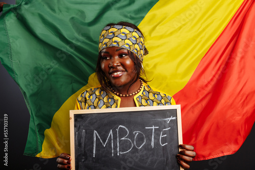 African woman in a national clothes of Congo holding a small blackboard with Hello word on his native language isolated on gray background photo