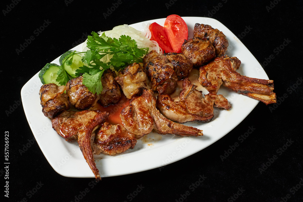 fried chicken legs and wings with fresh tomatoes and cucumbers on a black background