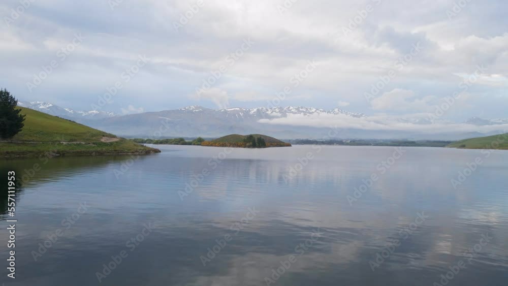 Low drone flight over Lake Opuha, New Zealand with snow-capped mountains in background Low drone flight over Lake Opuha, New Zealand with snow-capped mountains in background