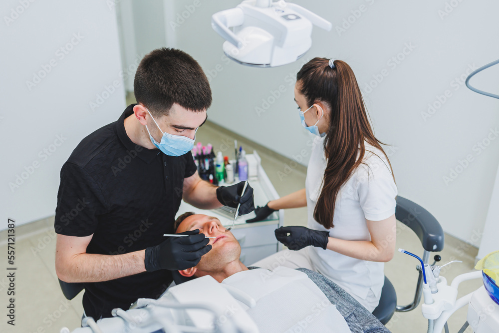 Obraz premium Dental office, examining a patient in a dental chair. Dental treatment is performed by a doctor and an assistant. Dental care.
