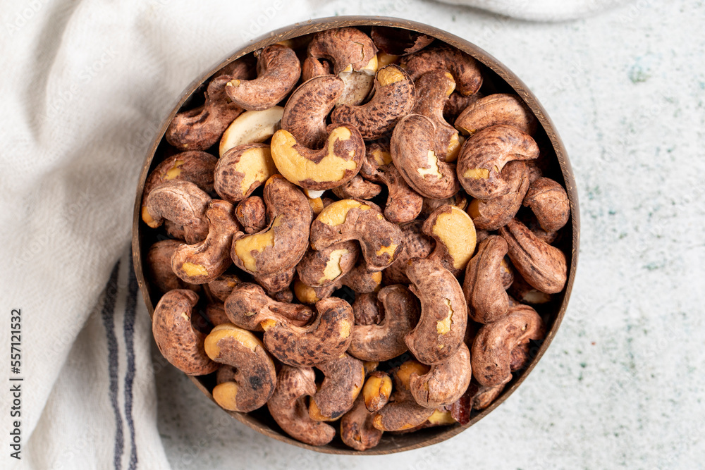 Roasted cashews on a gray background. Cashews in a coconut bowl. Top view Roasted cashews on a gray background. Cashews in a coconut bowl. Top view