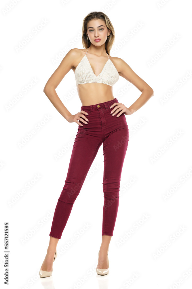 a young woman in burgundy jeans and top, and high heels shoes posing on a white background a young woman in burgundy jeans and top, and high heels shoes posing on a white background