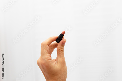 A woman's hand holds a lipstick miniature on a white background. Natural color lipstick sampler