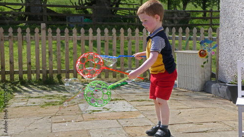 A child having fun with Soap Bubbles in a garden in summer photo