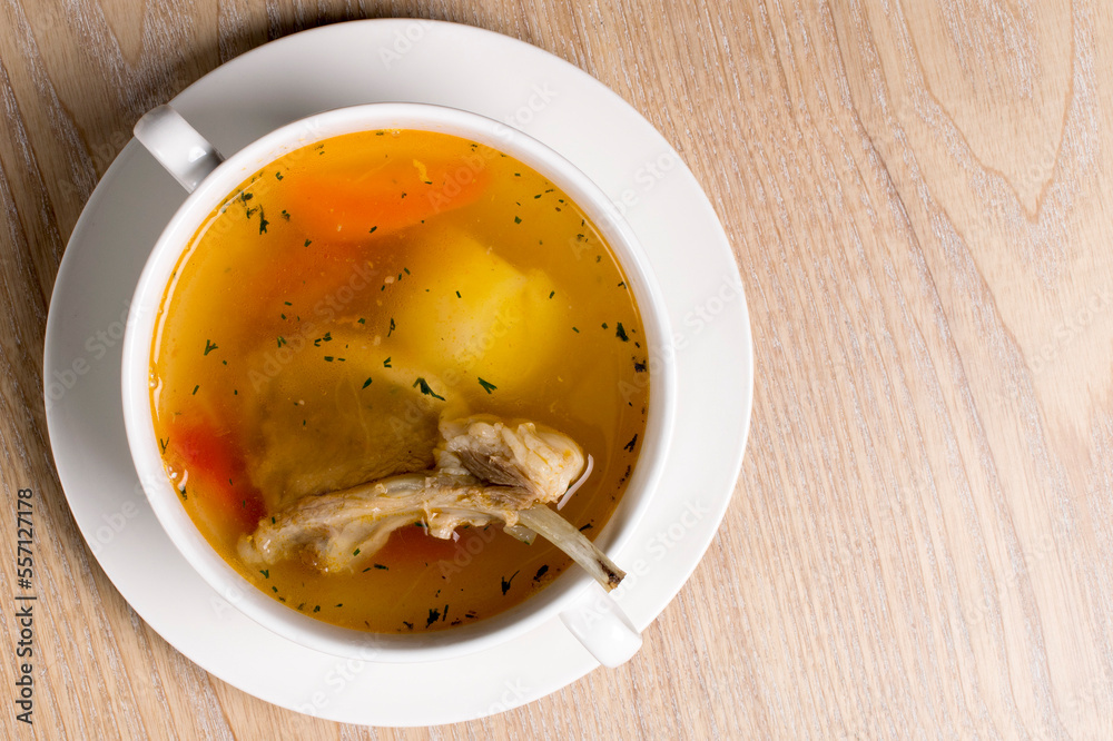soup made from lamb ribs with potatoes and carrots in a white plate on wooden background soup made from lamb ribs with potatoes and carrots in a white plate on wooden background
