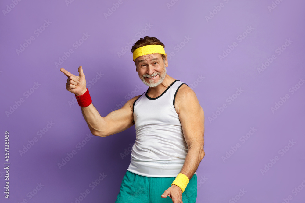 © puhhha - Smiling Man Pointing Hand. Positive Mature Man Pointing Away Paying Your Attention at Empty Space for Advertisement. Indoor Studio Shot Isolated on Violet Background © puhhha - Smiling Man Pointing Hand. Positive Mature Man Pointing Away Paying Your Attention at Empty Space for Advertisement. Indoor Studio Shot Isolated on Violet Background