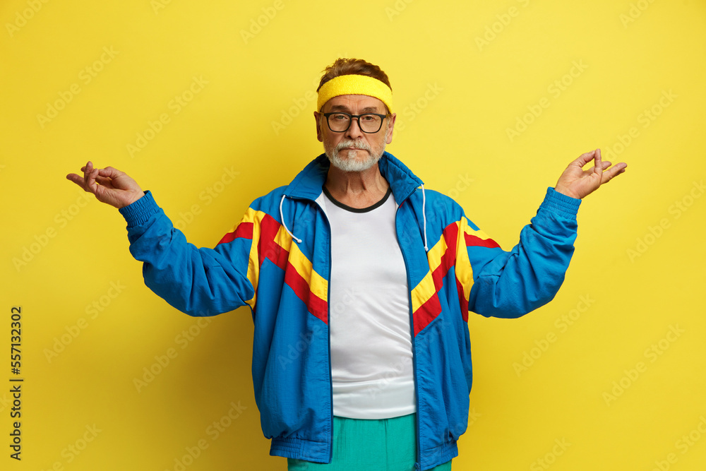Meditation. Portrait of Senior Man Relaxing and Doing Yoga Gesture with Fingers, Practicing Alone. Indoor Studio Shot Isolated on Yellow Background