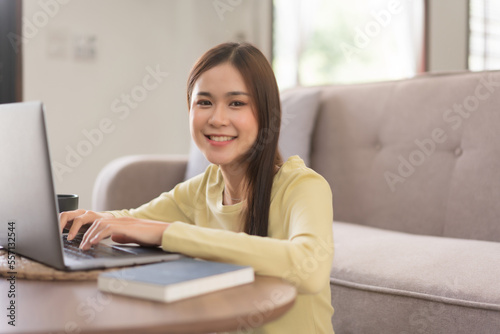 Concept of activity in home, Young woman is typing on laptop and smiling while sitting on the floor