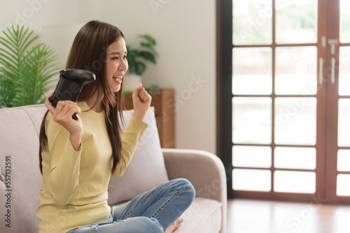 Relaxation concept, Young woman holding joystick and raising arms after winning in playing games