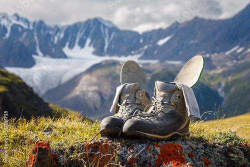 Trekking boots with insoles and socks dry on the background of a mountain valley. Boots in focus, background blurred. photo