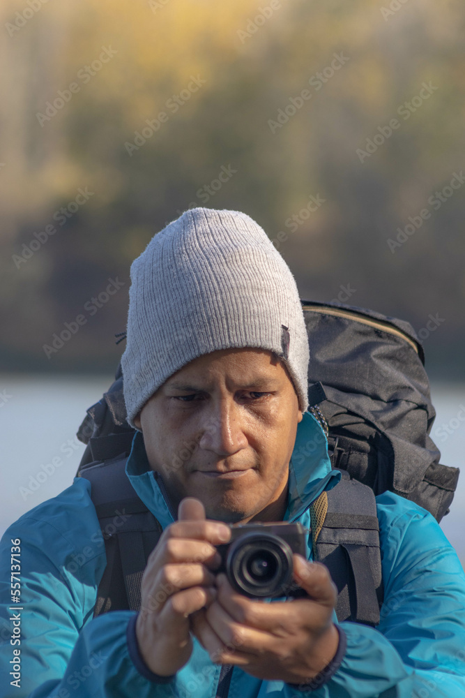 Obraz premium Portrait of traveler man at lake in autumn taking a photo with the digital camera