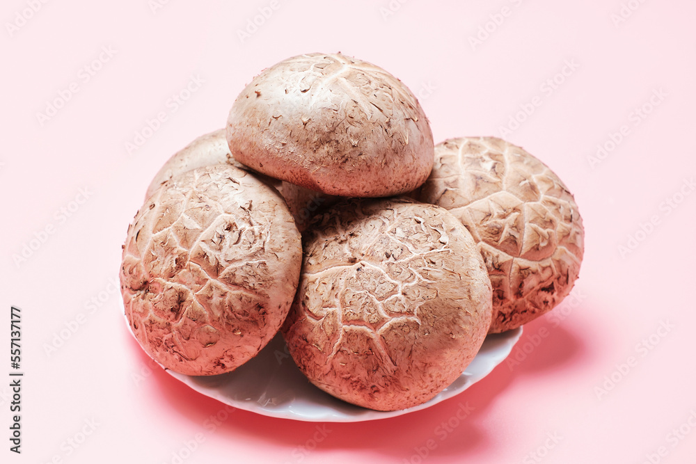 Shiitake mushrooms in a plate on a pink background close-up side view. Shiitake mushrooms in a plate on a pink background close-up side view.