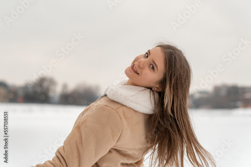 Smiling young woman with long hair enjoys winter nature in beige sheepskin coat. Warm womens clothing © somemeans