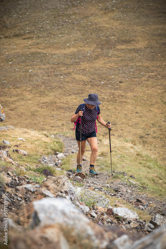 Woman hiker climbing the path to the highest point of the mountain with her walking sticks