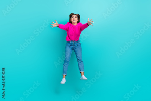 Full length photo of shiny excited girl dressed pink pullover jumping high open arms ready cuddles isolated teal color background