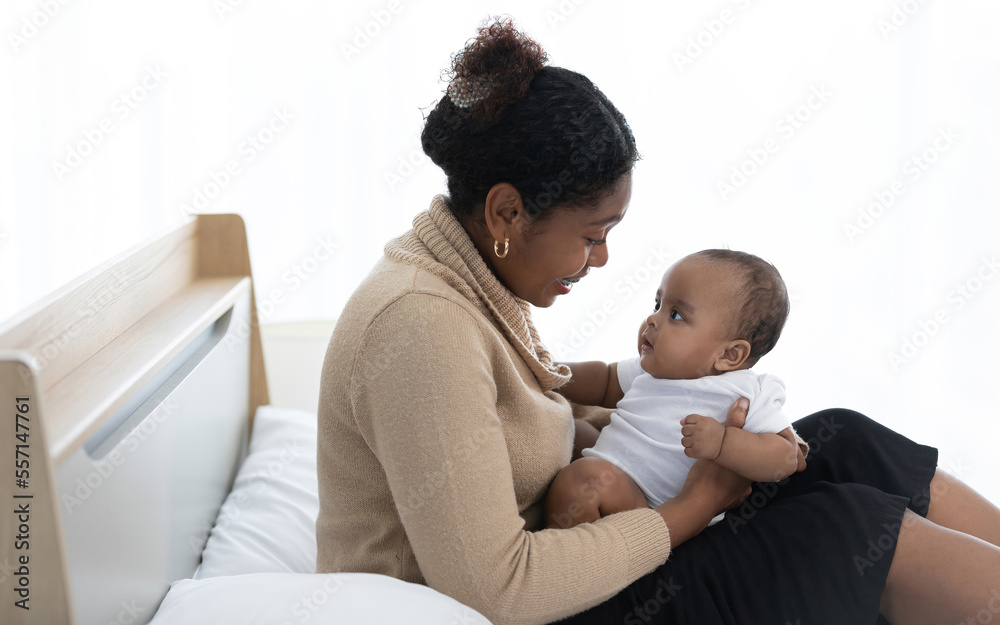 African young mother hugging and playing with her adorable baby on bed African young mother hugging and playing with her adorable baby on bed