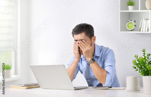 Asian man are stressed while overworked exhausted on laptop.