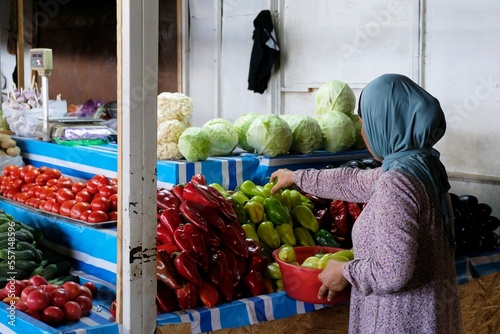 Kyrgyz woman is selling vegetables by stall in Osh Bazaar, central market in Bishkek, Kyrgyzstan.  photo