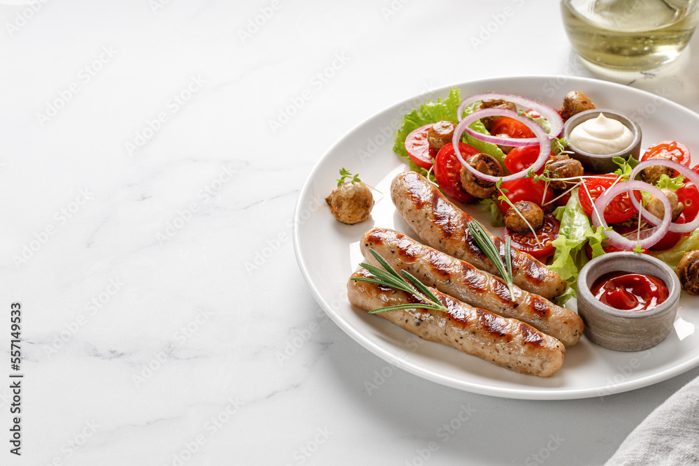 Grilled sausages with sauces, ketchup, rosemary and salad with tomatoes on a white plate. Dish, dinner idea.