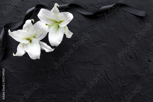 White liles flowers and black ribbon as symbol of the funeral. Mourning concept photo