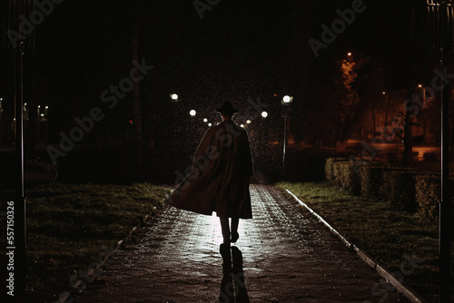 male detective in a hat and raincoat at night in a rainy city in the style of film noir photo