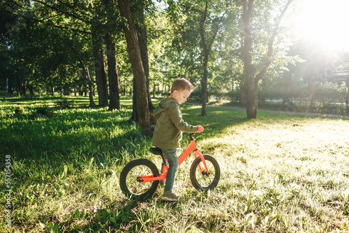 Little boy riding balance bikes in park.