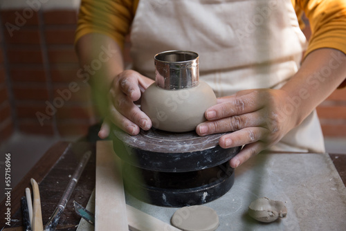 Close up hand of Asian Female using pottery wheel to make a tea pot in the workshop