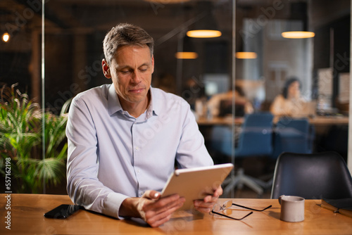 Portrait of businessman in office. Man using digital tablet. Businessman having video call. © JustLife