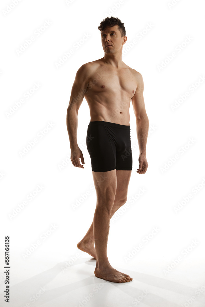 Portrait of mature handsome man posing shirtless in black boxers over white studio background. Muscular body shape. Men's health and beauty