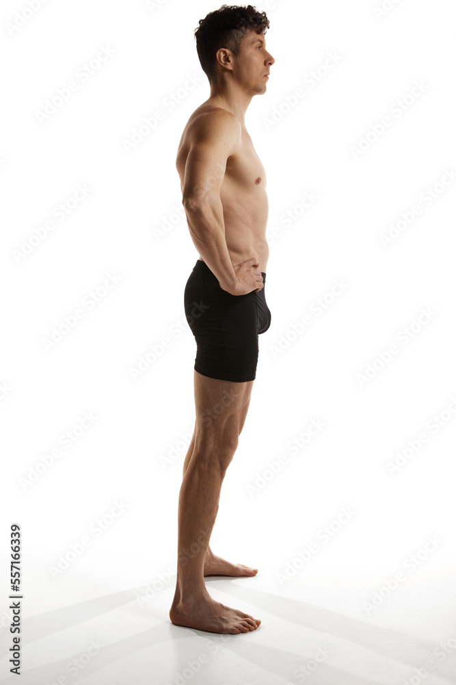 Obraz premium Side view photo of mature handsome man posing shirtless in black boxers over white studio background. Men's health and beauty