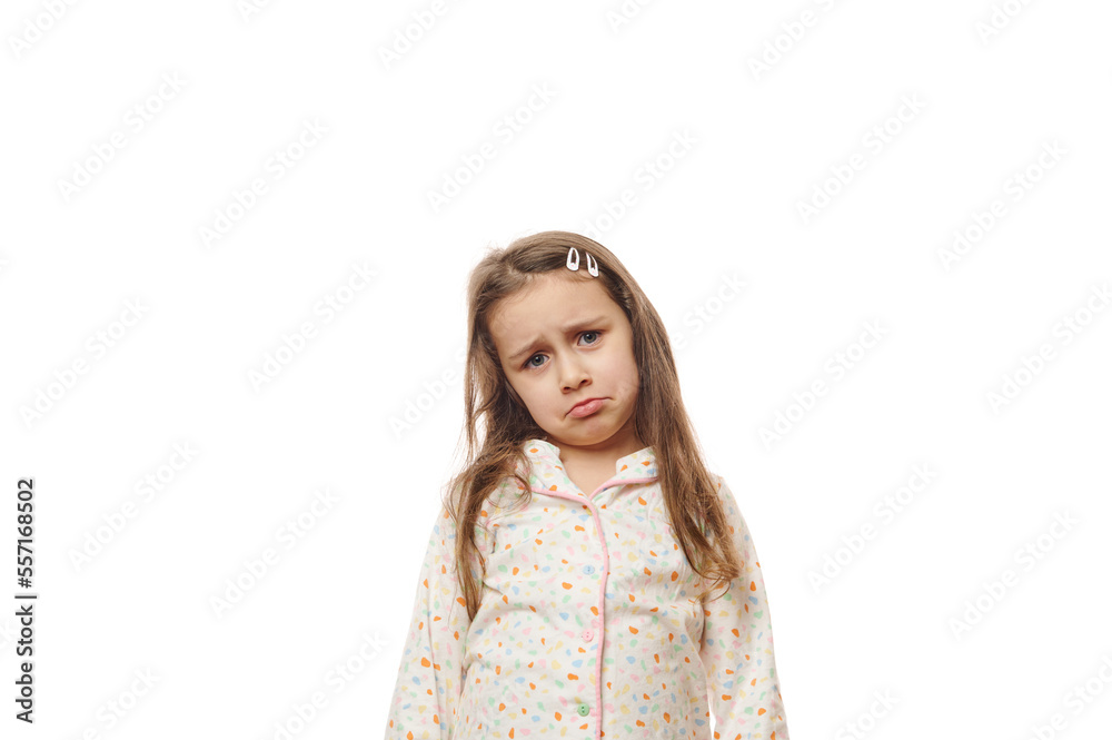 Depressed sad beautiful little child girl with long hair, in white pajamas, expressing sadness, looking at camera, isolated on white background. Loneliness, anxiety and despair Depressed sad beautiful little child girl with long hair, in white pajamas, expressing sadness, looking at camera, isolated on white background. Loneliness, anxiety and despair