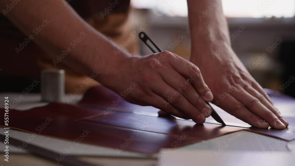 Leathersmith cuts material with special sharp knife at workplace in craft studio closeup. Tailor prepares leather product details. Tradition of manual work