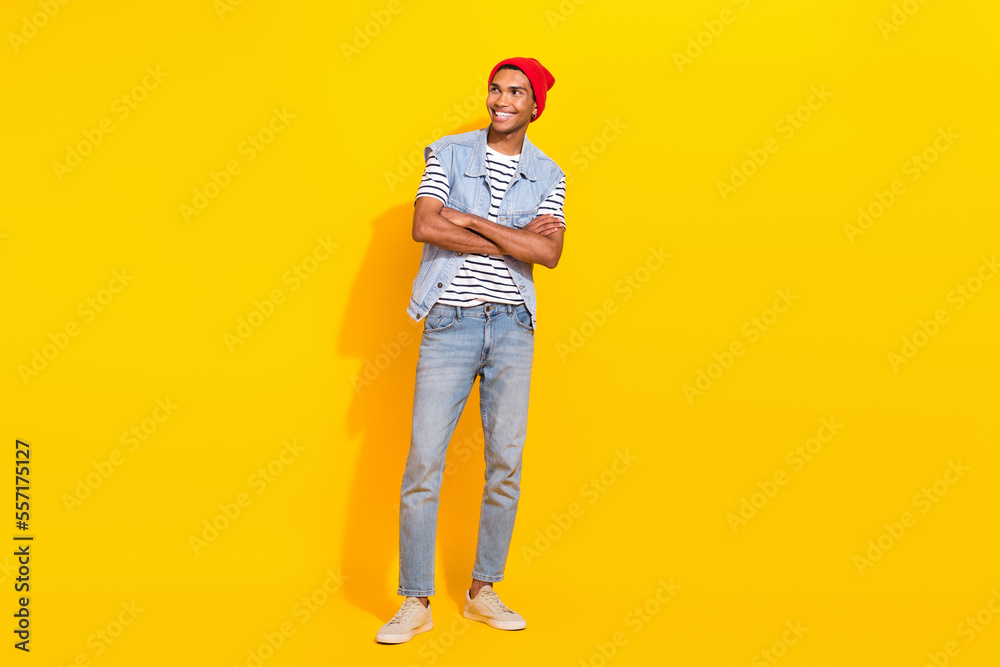 Full length photo of cheerful dreamy man wear jeans outfit looking empty space arms crossed isolated yellow color background Full length photo of cheerful dreamy man wear jeans outfit looking empty space arms crossed isolated yellow color background