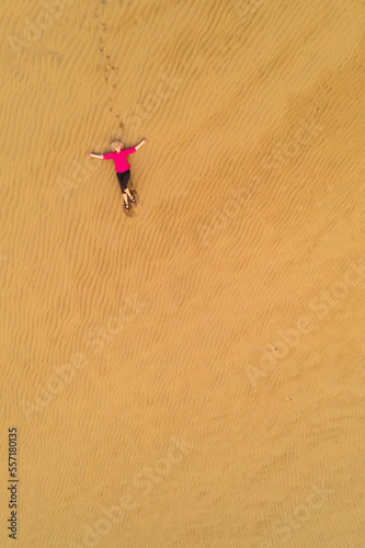Caucasian white woman relaxing in the dunes. Maspalomas dunes in Gran Canaria, view from above. Peace of mind. Meditation