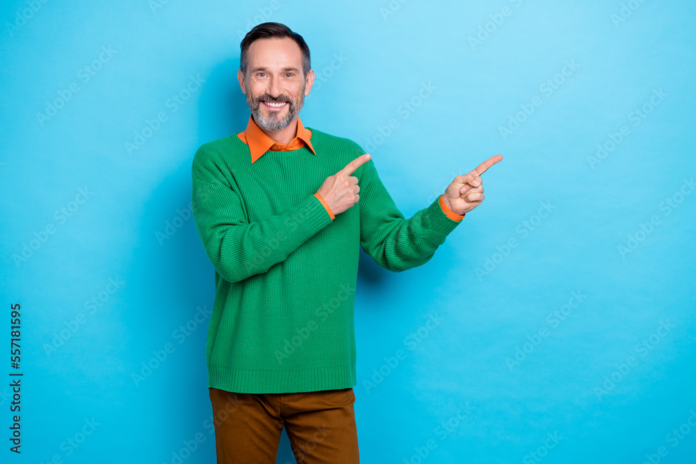 Photo of positive person toothy smile indicate fingers empty space isolated on blue color background Photo of positive person toothy smile indicate fingers empty space isolated on blue color background