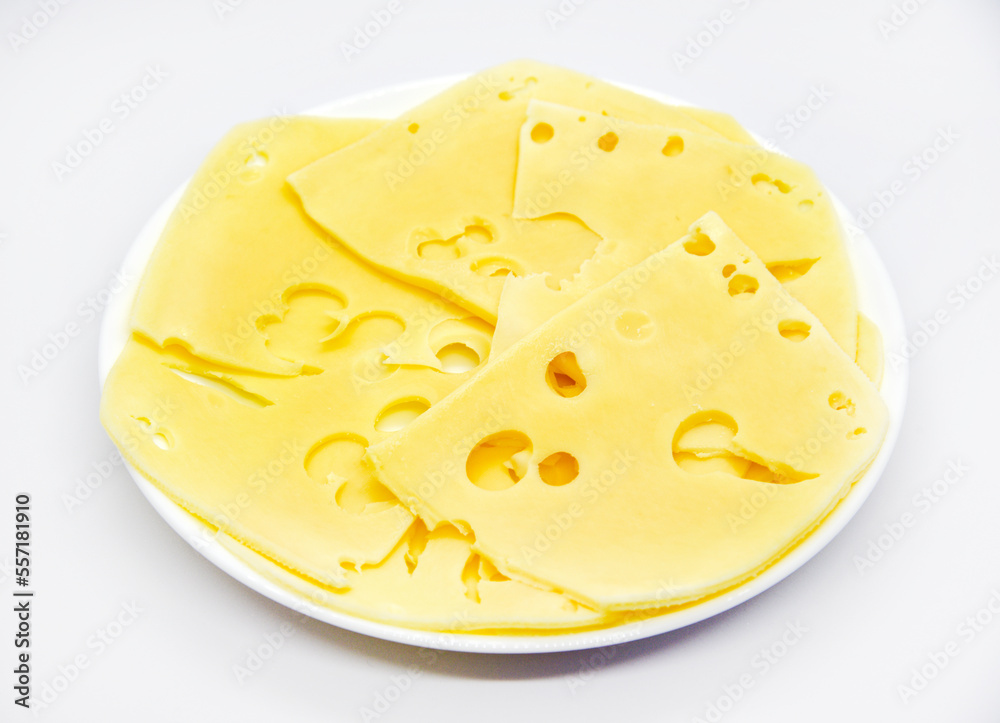 Sliced pieces of yellow cheese with holes on the plate. Chopped cheese close-up. Delicious cheese slices. Sliced pieces of yellow cheese with holes on the plate. Chopped cheese close-up. Delicious cheese slices.