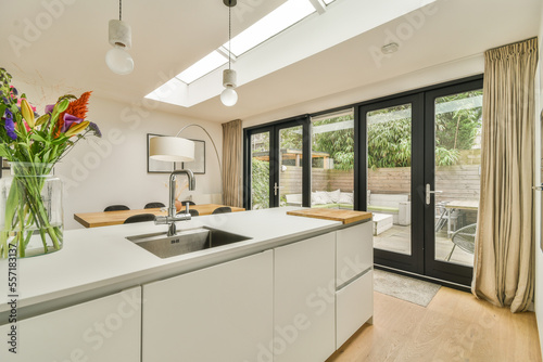 a modern kitchen with white cabinets and an open skylight above the counter area in the room is light wood flooring photo