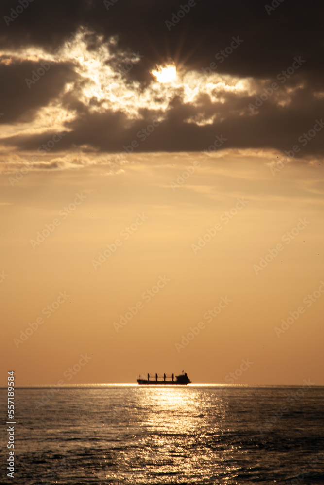 a giant cargo ship passing the sun during the sunset at the baltic sea in Germany 