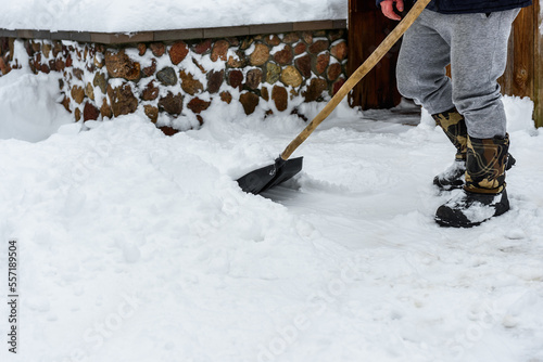 Human cleaning snow with shovel near house.