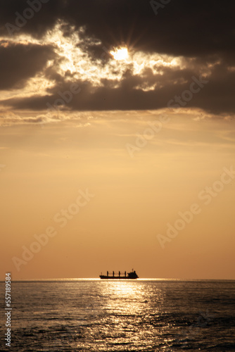 a giant cargo ship passing the sun during the sunset at the baltic sea in Germany  © Michael
