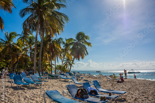 Dominican Republic. 20 NOVEMBER 2021. Caribbean beach with a lot of palms and white sand, sunbeds. Sunny warm day at the sea under palm trees. Sun loungers under palm trees