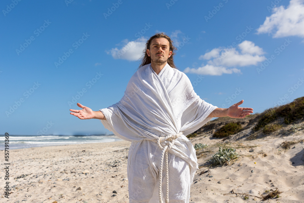 Jesus-like man with open arms on beach