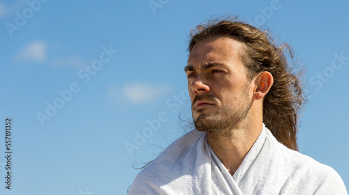 Compassionate man who resembles Christ looking into future in white robe with copy space